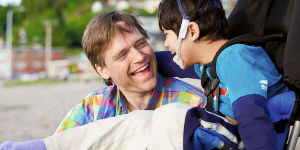 Vater und Kind mit Behinderung lachen zusammen