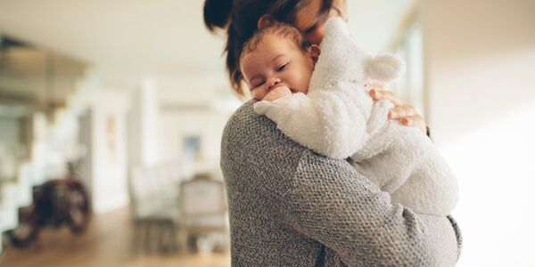 Mutter hält Baby im Arm im Wohnzimmer